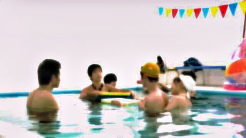 Asian group in swimsuits playfully swimming underwater in pool