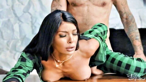 Busty Latina MILF exposes huge tits from green plaid shirt as tattooed stud gropes her on table