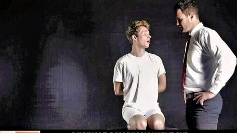 Elder in suit seduces curious young missionary boy in white shirt, intimate gaze