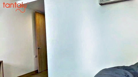 Empty white bedroom interior with wooden door, air conditioner, and gray bed sheets