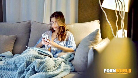 Brunette in blue lingerie and glasses relaxing with phone on couch