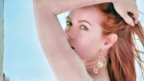 Seductive freckled redhead with green eyes poses topless hand in hair