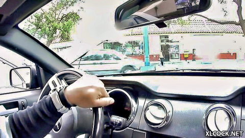 Tanned hand gripping steering wheel tightly in Mustang car POV driving past gas station