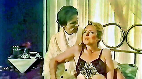 Vintage blonde in lace bra embraced by man in robe, classic 1981 porn