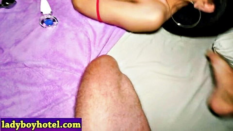 Naked amateur woman with hoop earrings lies on purple bed exposing ass and pussy beside hairy man's thigh