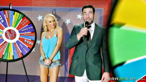 Busty blonde in turquoise tube top and tiny shorts handcuffed on porn wheel of fortune game show with suited host