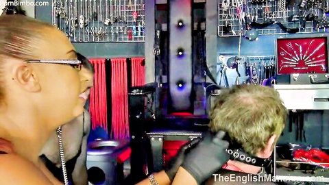 Domina Pandora in red top and gloves dominates submissive man in BDSM scene