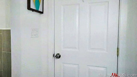 Empty white bathroom door with teal art and touchmywife.com watermark in amateur wife porn video