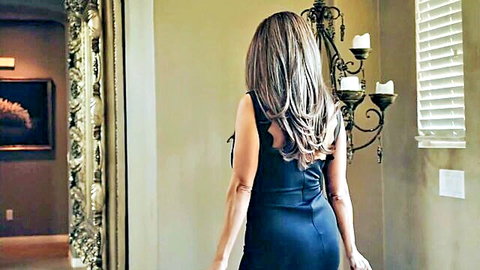 Brunette MILF in tight blue dress teases big ass from behind, seductive glance over shoulder