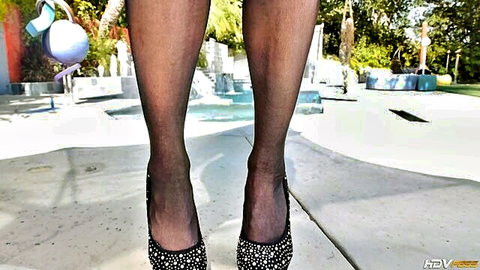 Sexy long legs in sheer black stockings and sparkly high heels by the pool