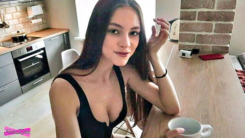 SolaZola teasing in low-cut black tank top, holding tea cup with deep cleavage