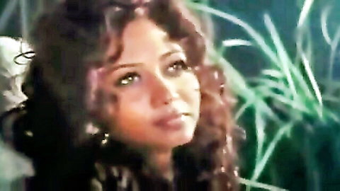 Sensual closeup of sexy Indian woman with curly hair and piercing green eyes in erotic gaze