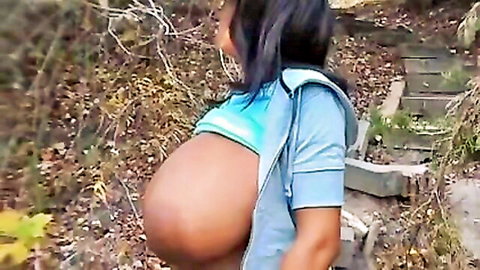 Ebony babe with massive hanging tits and pregnant belly exposed under open hoodie on forest trail
