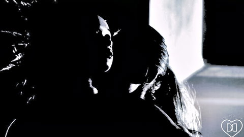 Seductive brunette in shiny black dress with long hair in dramatic shadowy lighting