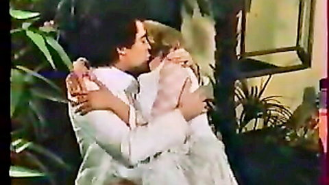 Vintage blonde woman passionately French kissing long-haired hunk in white suit retro style