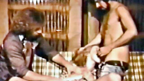 Bearded man in jacket grabs hairy friend's exposed hard cock in vintage gay scene