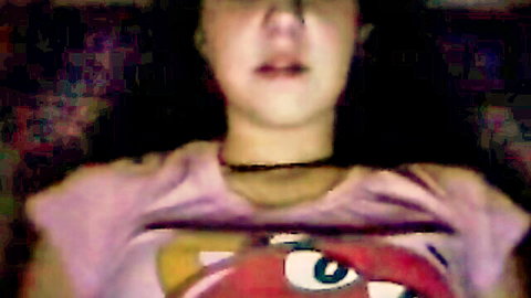 Brunette teen amateur webcam girl makes funny open-mouth face in loose pink cartoon t-shirt