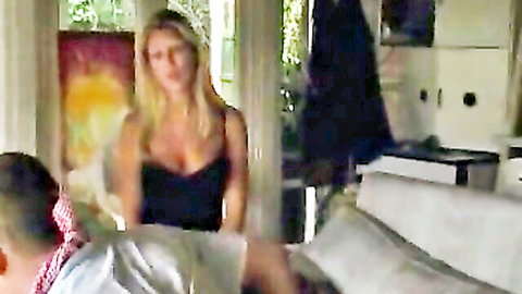 Boss Belle blonde in low-cut black dress, seductive cleavage view