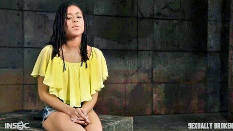 Kira Noir ebony beauty in yellow top and shorts, posed in bondage scene