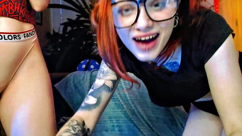 Redhead with glasses and tattoos in colorful underwear, smiling seductively in lesbian tease