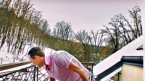 Man in pink striped shirt leaning on snowy balcony, bisexual threesome preview