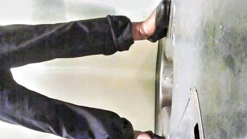 Voyeur shot of East Asian woman's legs in black stockings stepping on public restroom urinal