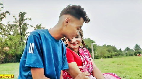 Romantic Indian couple in saree and t-shirt cuddling closely on green grass field outdoors