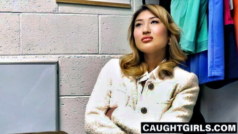 Busty Asian Mina Luxx in white jacket, arms crossed seductively
