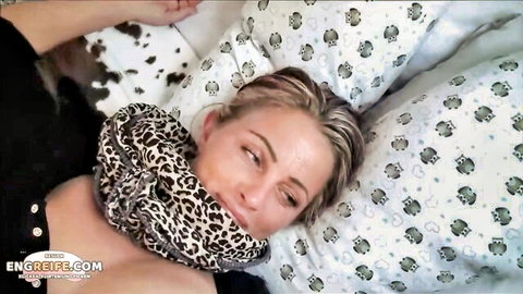 Seductive blonde in leopard scarf lies on bed, teasing gaze