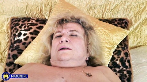 Mature blonde woman lying nude with seductive expression