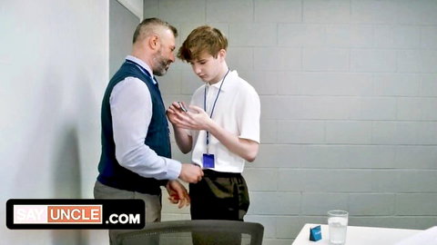 Hunky DILF teacher leans close to cute young twink student checking phone in school gay tease