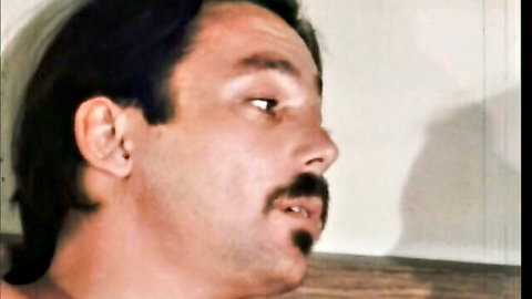Close-up profile of intense hairy mustached man in vintage retro porn scene