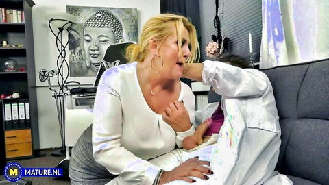 Mature blonde MILF in blouse grabs crotch bulge through pants on couch