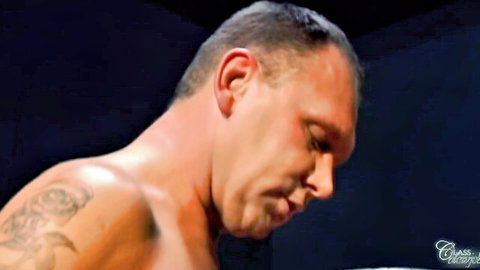 Shaved head muscular man with tattoos looking down during intense oral action