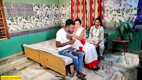 Indian MILF in red saree embraced by man on bed, watched by another woman in taboo hookup