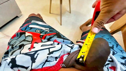 Black man measuring his thick cock with ruler in pulled-down Jordan shorts