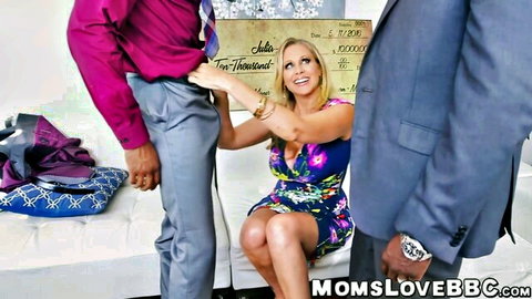 Blonde MILF in floral dress gropes big black cock bulge while two suited men stand over her