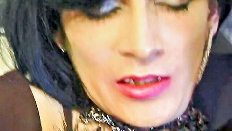 Seductive crossdresser close-up with dark hair, heavy makeup, red lips