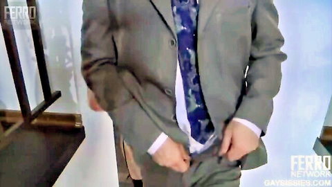Crossdresser Ferro in gray suit and camo tie, teasing at pants in mirror