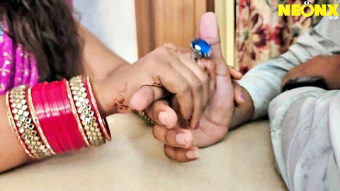 Indian couple passionately holding hands with red bangles henna and blue ring in romantic tease