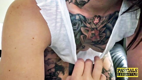 Heavily tattooed brunette with torn white tank top exposing intricate chest tattoos