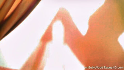 Erotic silhouette of nude Indian babe posing seductively against orange curtains