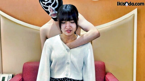 Masked luchador man grabs Asian babe's shoulders from behind while she sits clothed on red couch
