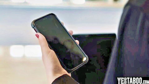 Woman in dark clothes holding black smartphone and laptop at airport terminal