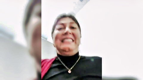 Smiling mature Latina MILF in red shawl and black top, seductive gaze