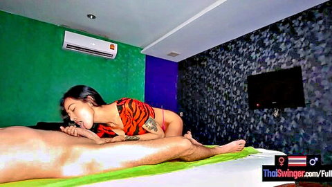 Thai woman in tiger bikini gives blowjob to naked man on massage bed
