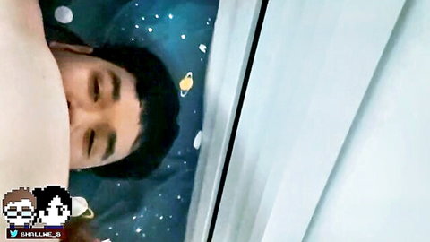 Shirtless Asian man lying on starry bed with hand caressing his bare chest