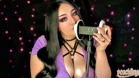 Busty babe in purple harness bra teases microphone with lips showing massive cleavage for ASMR big tits play