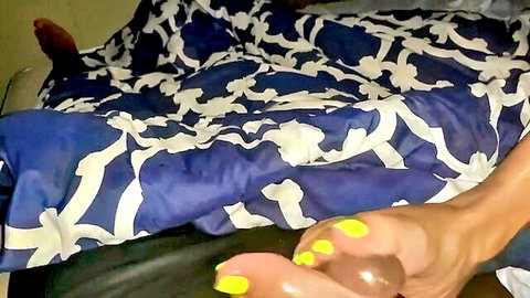 Ebony babe with yellow toenails gives footjob to thick brown cock on bed