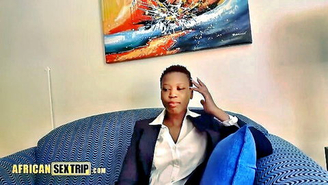 Hot African ebony woman in white blouse and blazer sitting seductively on couch